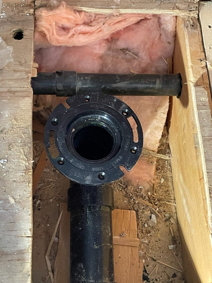 New toilet flange set into the subfloor on a fresh ABS drain connection.