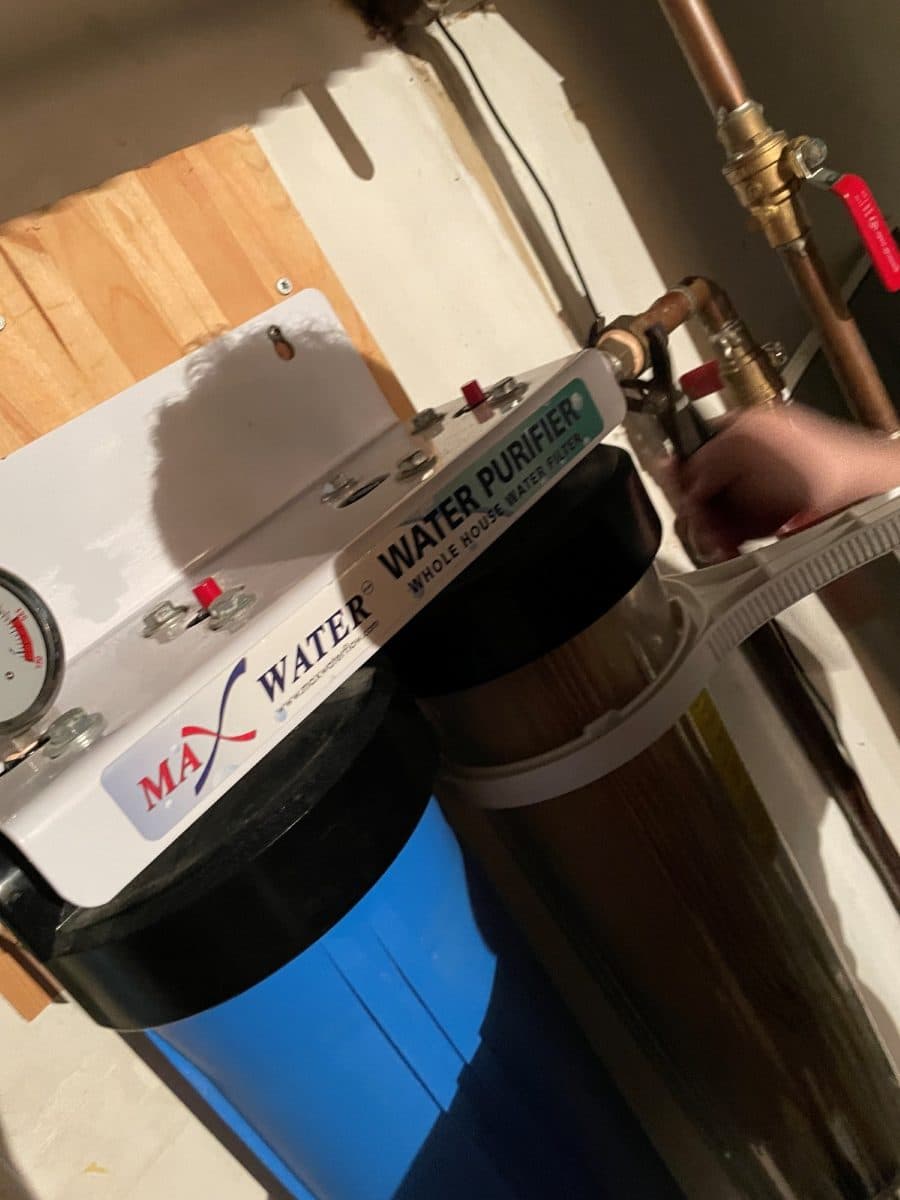 Two-stage whole-home water filtration system plumbed into copper lines on a basement wall.