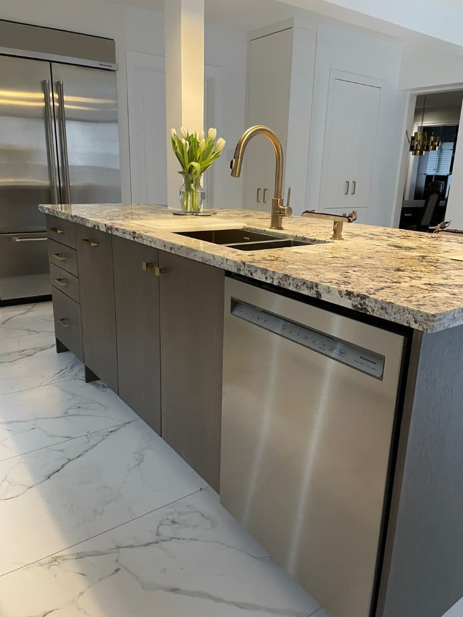 Finished kitchen island with an undermount sink and brushed brass pull-down faucet in a marble worktop.